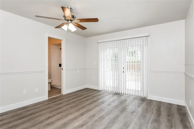 an empty room with wooden floor fan and windows