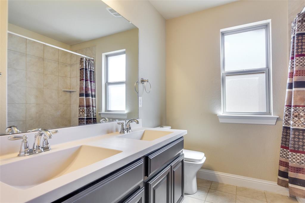 1505 5th Street Argyle, TX 76226 - Photo 21 of 25 a bathroom with a granite countertop sink a toilet and a window
