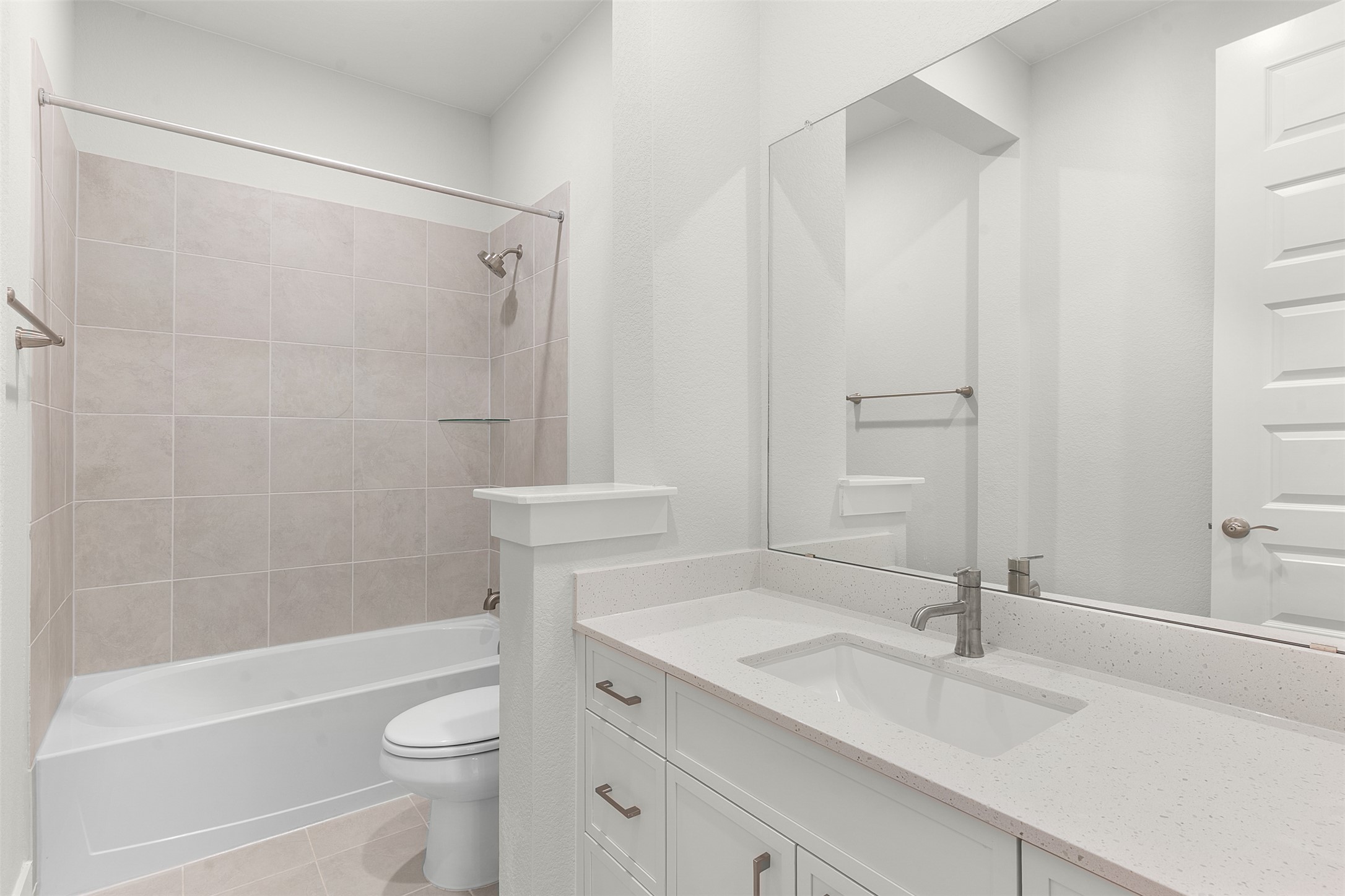 1129 Pansy Trail Georgetown, TX 78628 - Photo 10 of 29 Bathroom featuring a white vanity with integrated sink, a large wall-mounted mirror, a tub/shower combination with light-colored tile surround, and a toilet