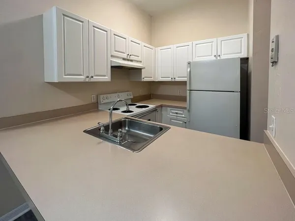 a kitchen with stainless steel appliances granite countertop a refrigerator a stove a white sink and a granite counter tops
