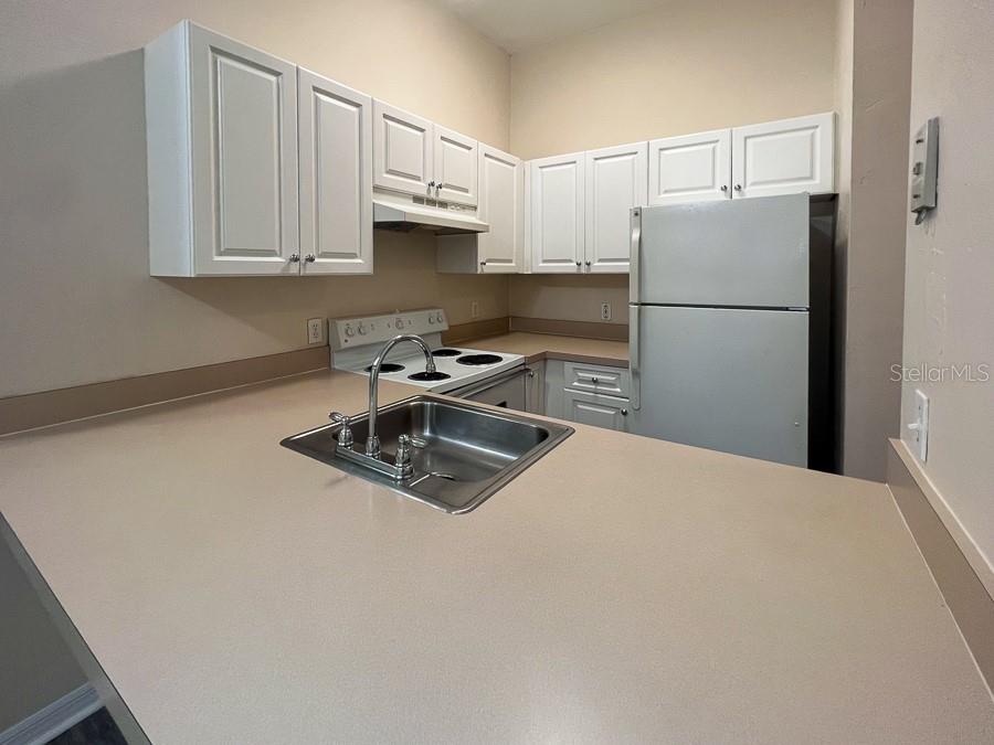 3911 Southwest 27th Street, Unit 8 Gainesville, FL 32608 - Photo 9 of 16 a kitchen with stainless steel appliances granite countertop a refrigerator a stove a white sink and a granite counter tops