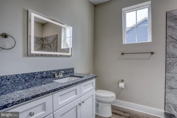 a bathroom with a granite countertop sink a toilet and a window