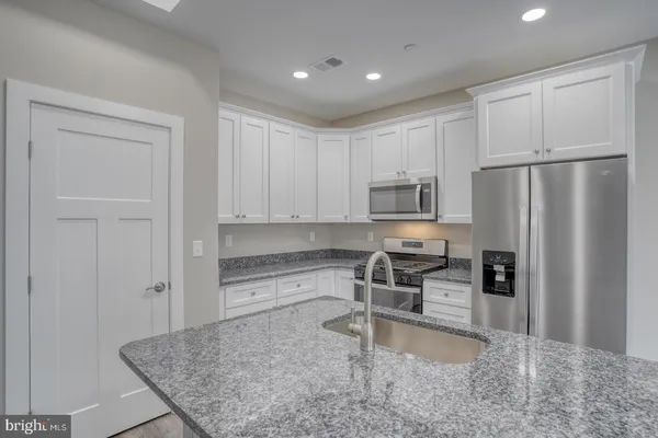 a kitchen with granite countertop a refrigerator and a sink