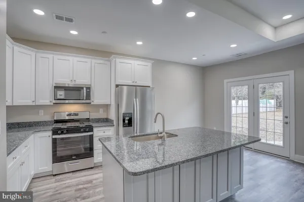 a kitchen with kitchen island granite countertop a stove and a sink
