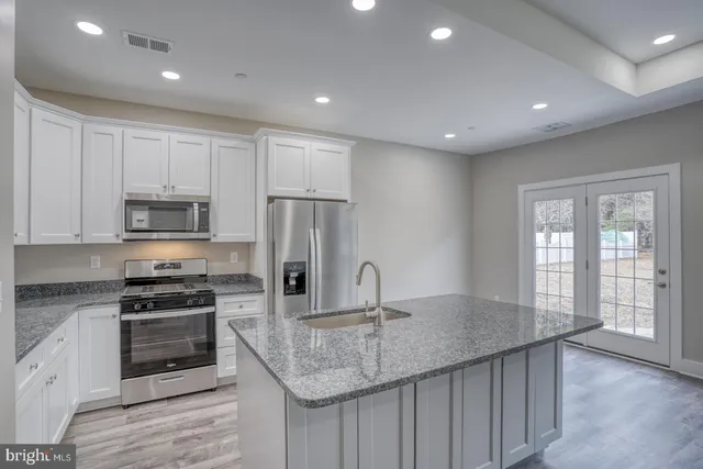 a kitchen with kitchen island granite countertop a stove and a sink