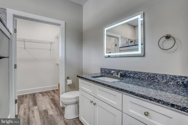 a bathroom with a granite countertop toilet a sink and mirror