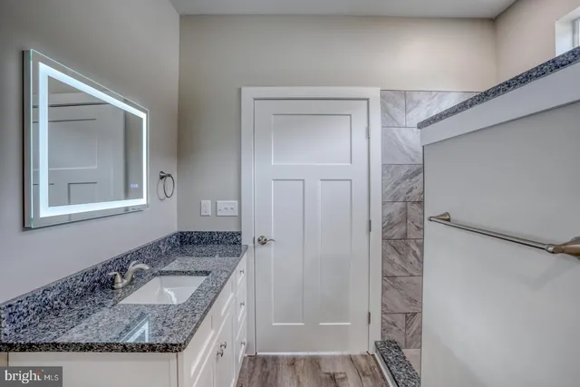 a bathroom with a granite countertop sink and a mirror