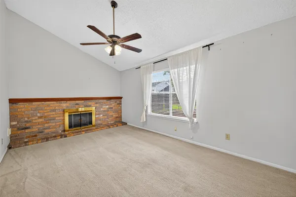 a view of a livingroom with a ceiling fan a fireplace and windows