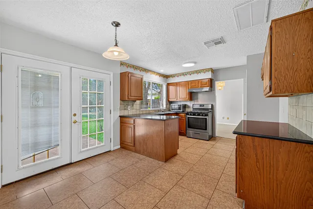 a kitchen with granite countertop a stove a sink dishwasher and a refrigerator with wooden floor