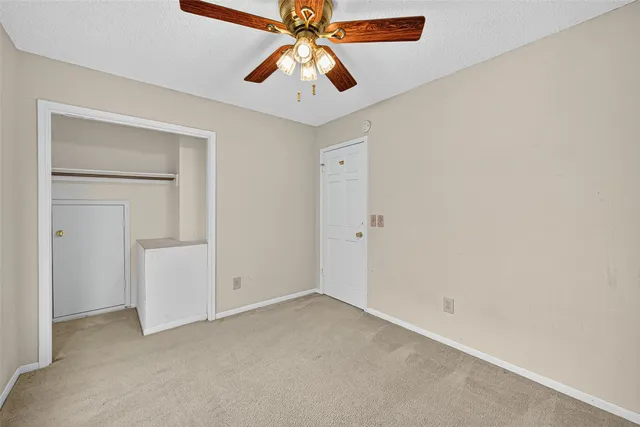 a view of an empty room with window and a kitchen view
