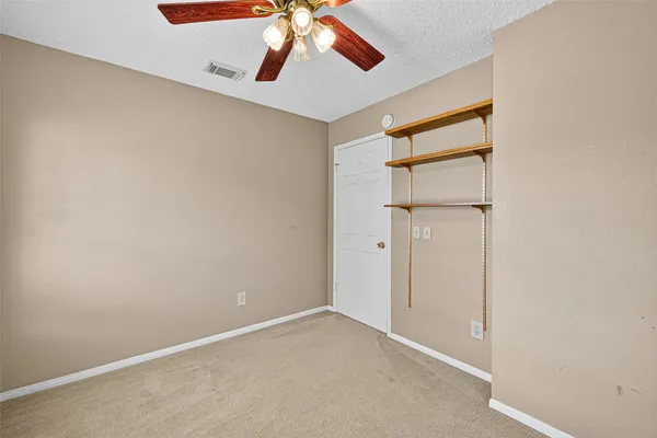 an empty room with chandelier fan and windows