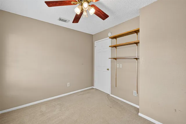 an empty room with chandelier fan and windows