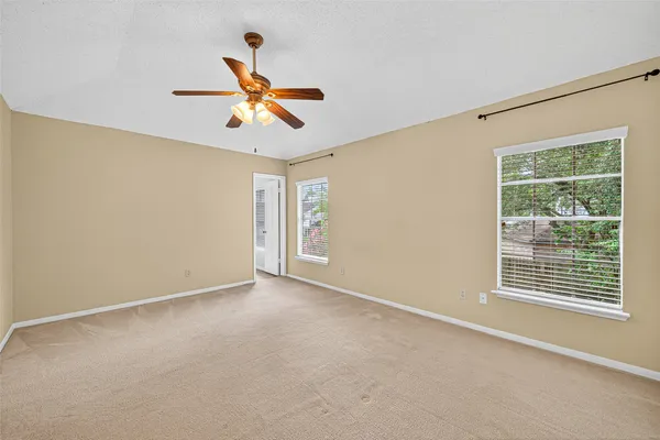 a view of an empty room with a ceiling fan and window
