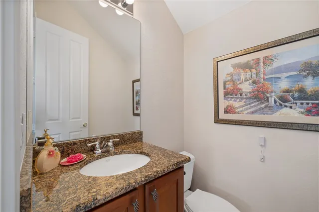 a bathroom with a granite countertop sink vanity mirror and toilet