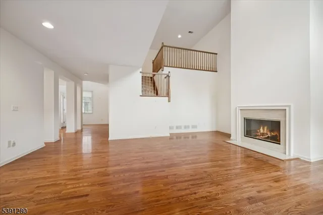 an empty room with wooden floor fireplace and windows