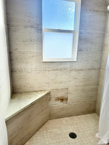 4375 West 4500 S Road Deseret, UT 84624 - Photo 15 of 20 Shower with light-toned rectangular wall tiles, a corner bench with a light-colored countertop, a frosted window, and square-patterned floor tiles