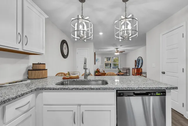 a kitchen with granite countertop stainless steel appliances a chandelier and cabinets