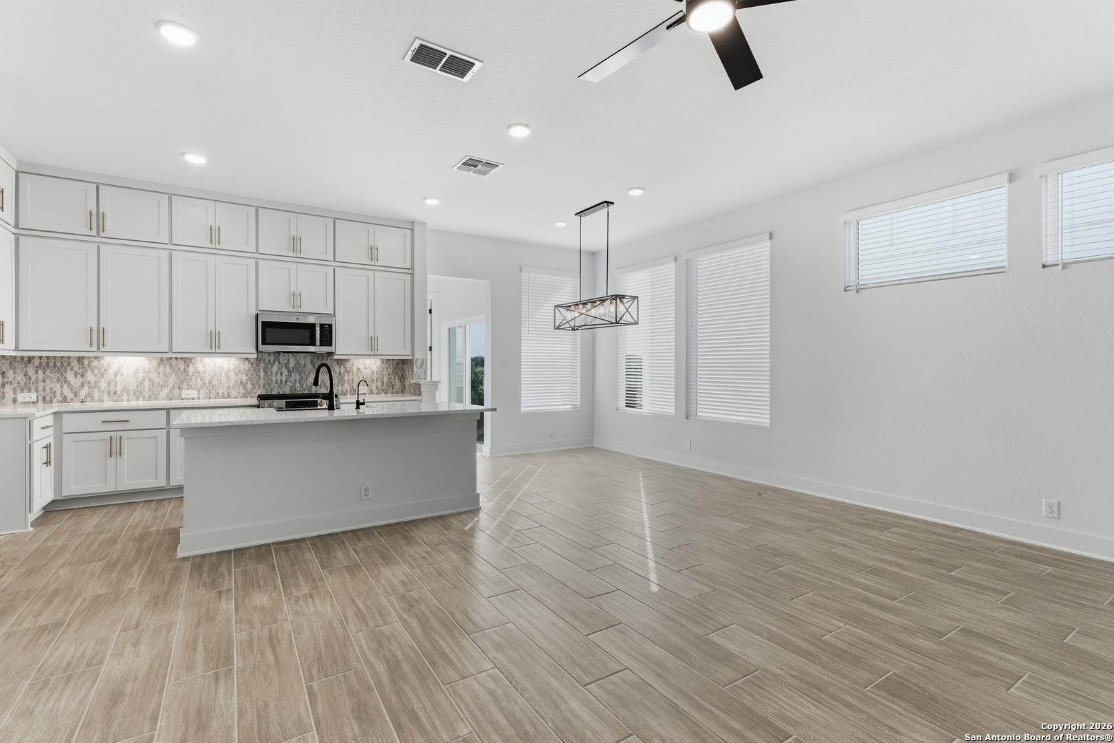 20675 Huebner Road, Unit 527 San Antonio, TX 78258 - Photo 12 of 43 a large kitchen with white cabinets a sink dishwasher a stove and a refrigerator with wooden floor