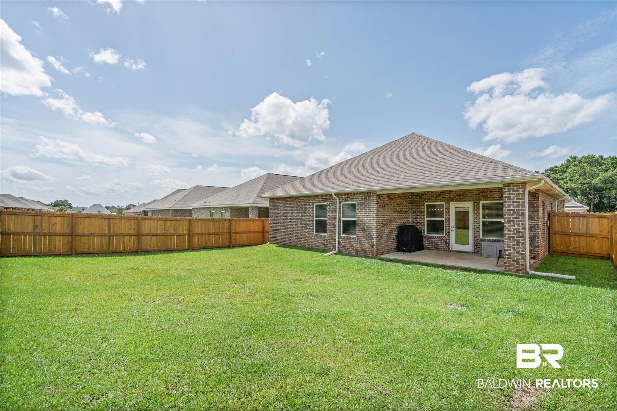 10541 Heirloom Road South Mobile, AL 36608 - Photo 18 of 23 Backyard featuring a green lawn, wood fence, and a brick exterior home with a covered patio