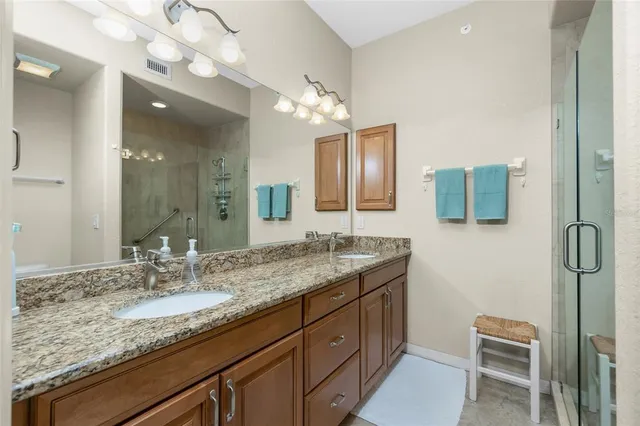 a bathroom with a granite countertop sink a mirror and shower