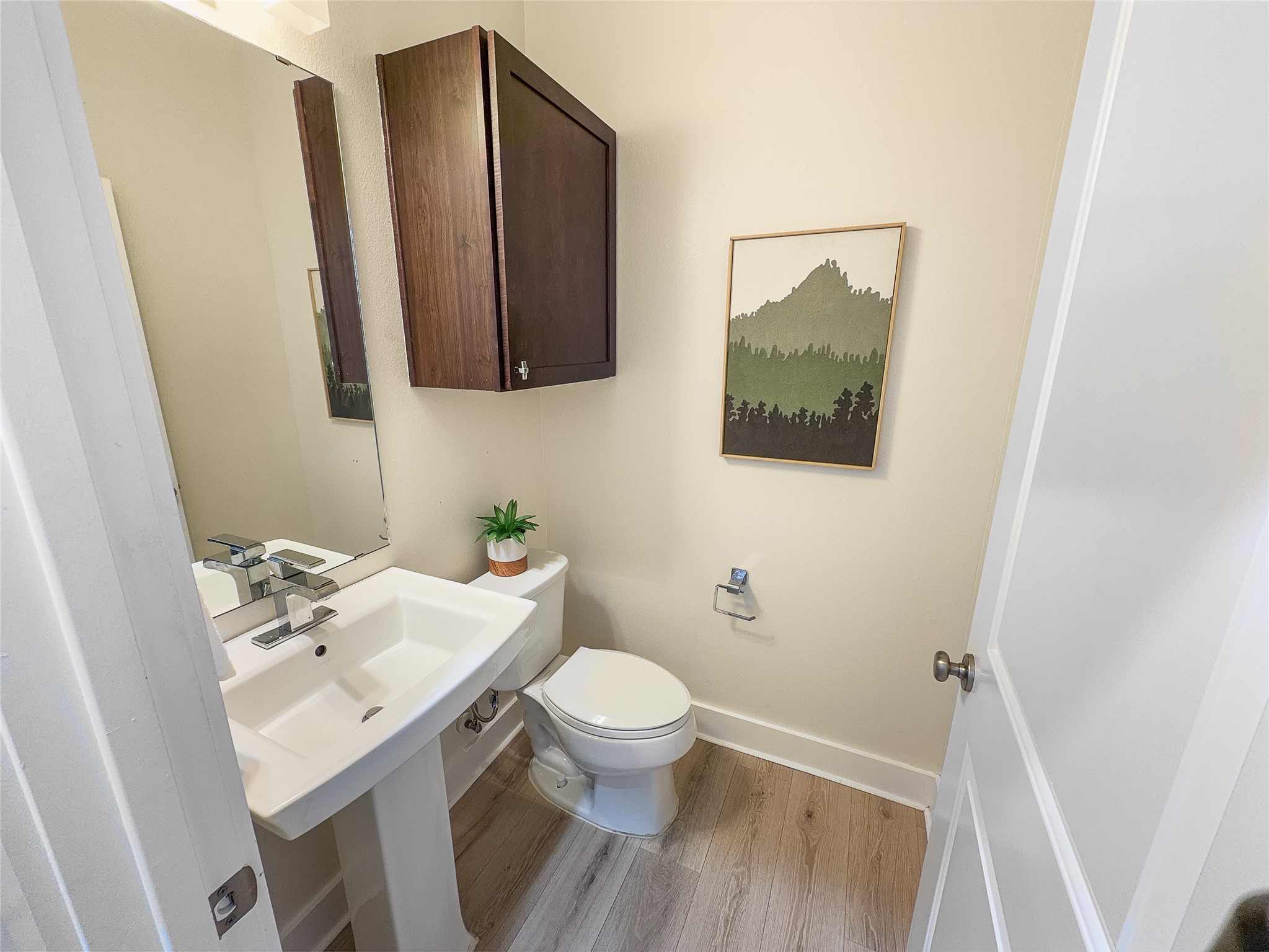 4120 Valley View Road, Unit B Austin, TX 78704 - Photo 14 of 17 Step into a well-appointed powder room featuring a sleek pedestal sink and wood-look flooring.