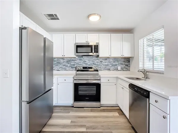 a kitchen with stainless steel appliances white cabinets white stove a refrigerator and a microwave