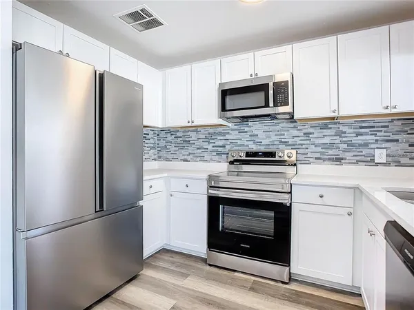 a kitchen with cabinets stainless steel appliances a sink and a window