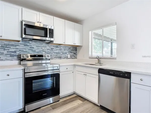 a kitchen with a sink window and wooden floor