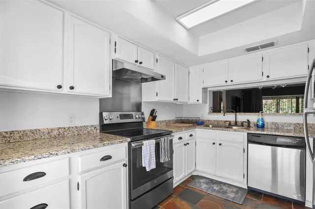 a kitchen with stainless steel appliances granite countertop a sink stove and cabinets