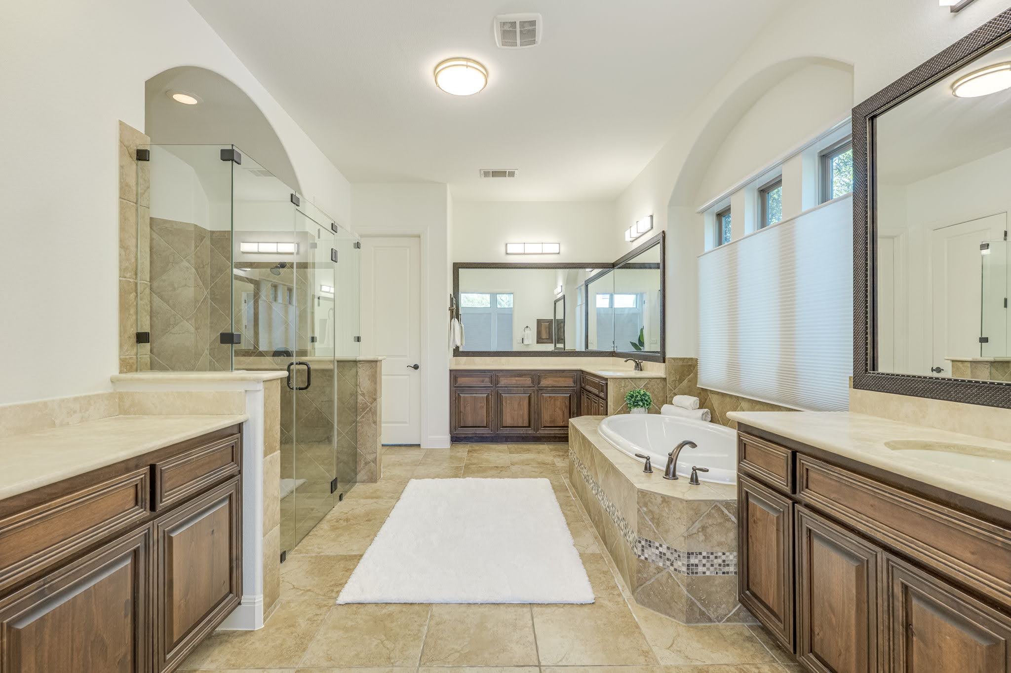11612 Shoreview Overlook Austin, TX 78732 - Photo 28 of 40 Warm tile flooring and a soaking tub define this elegant primary bath with dual vanities.