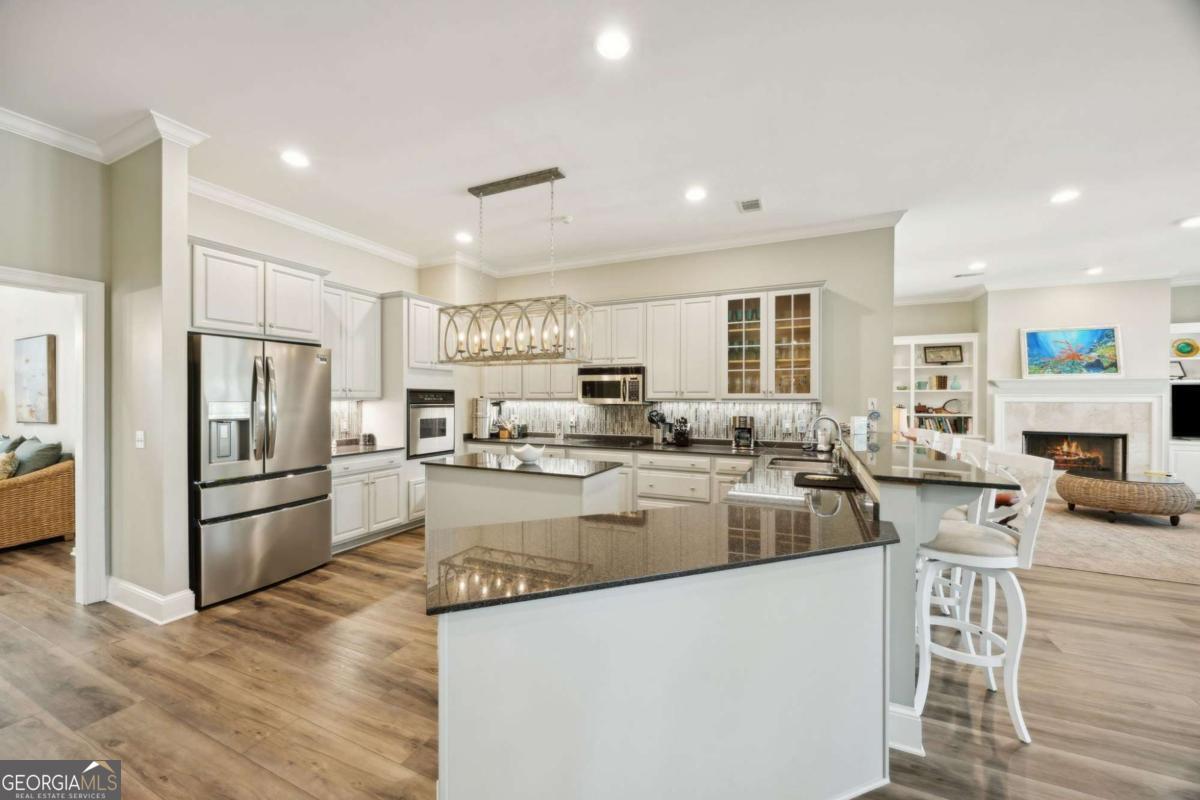343 Major Wright Road St. Simons, GA 31522 - Photo 11 of 53 a kitchen with stainless steel appliances granite countertop a refrigerator oven a sink dishwasher and white cabinets with wooden floor