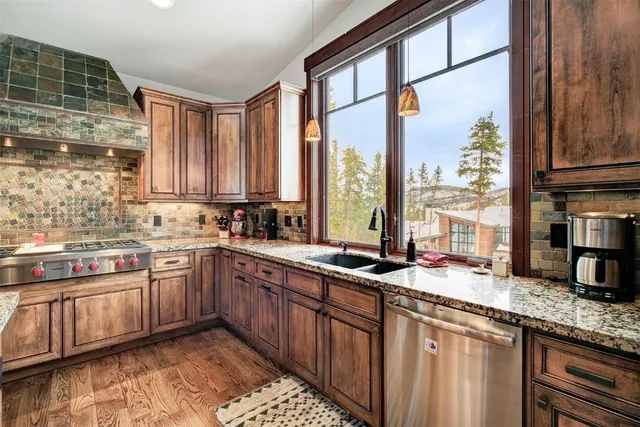 a kitchen with stainless steel appliances granite countertop a sink a stove and a wooden cabinets