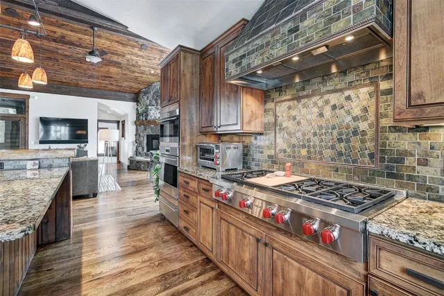 a kitchen with stainless steel appliances granite countertop a stove a sink dishwasher and cabinets with wooden floor