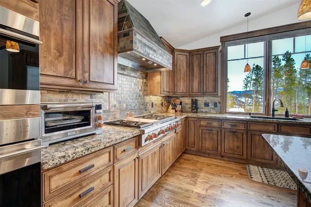 a kitchen with stainless steel appliances granite countertop a stove a sink and a refrigerator