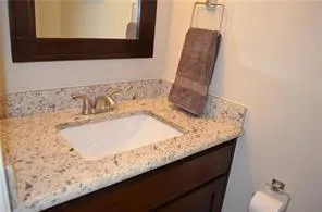 a bathroom with a granite countertop sink and a mirror