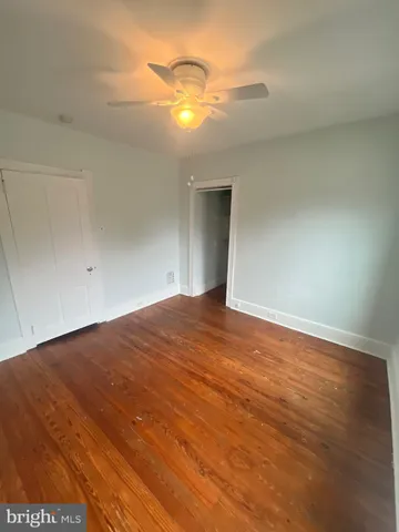 an empty room with wooden floor and fan