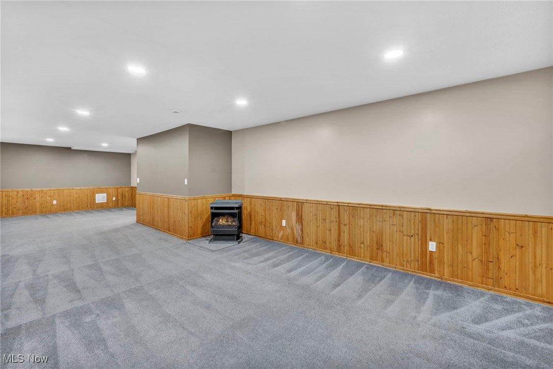 3181 Ridgewood Road Medina, OH 44256 - Photo 37 of 50 Carpeted spare room featuring wooden walls and a wood stove
