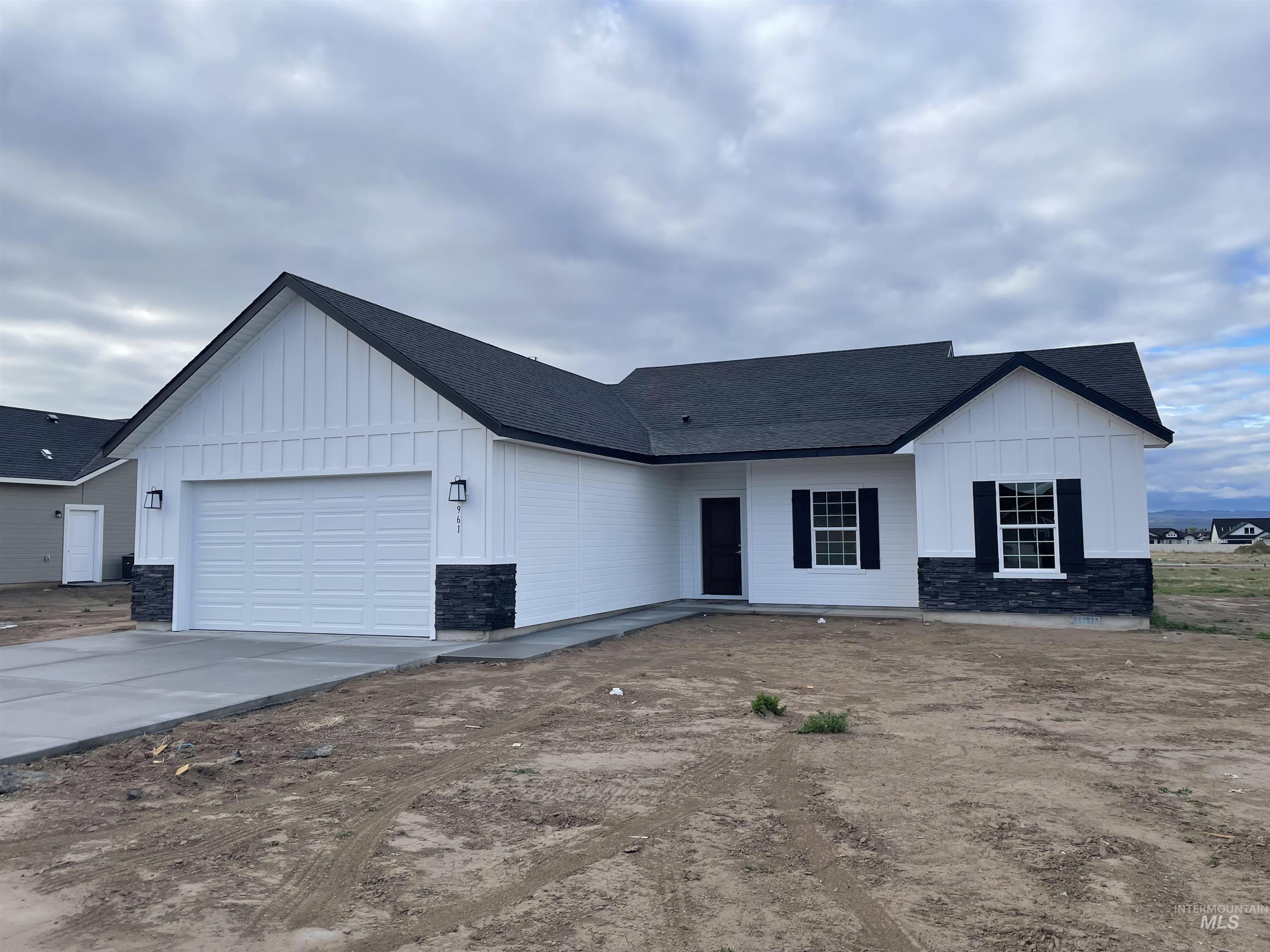 Modern inspired farmhouse featuring board and batten siding, an attached garage, a shingled roof, concrete driveway, and stone siding