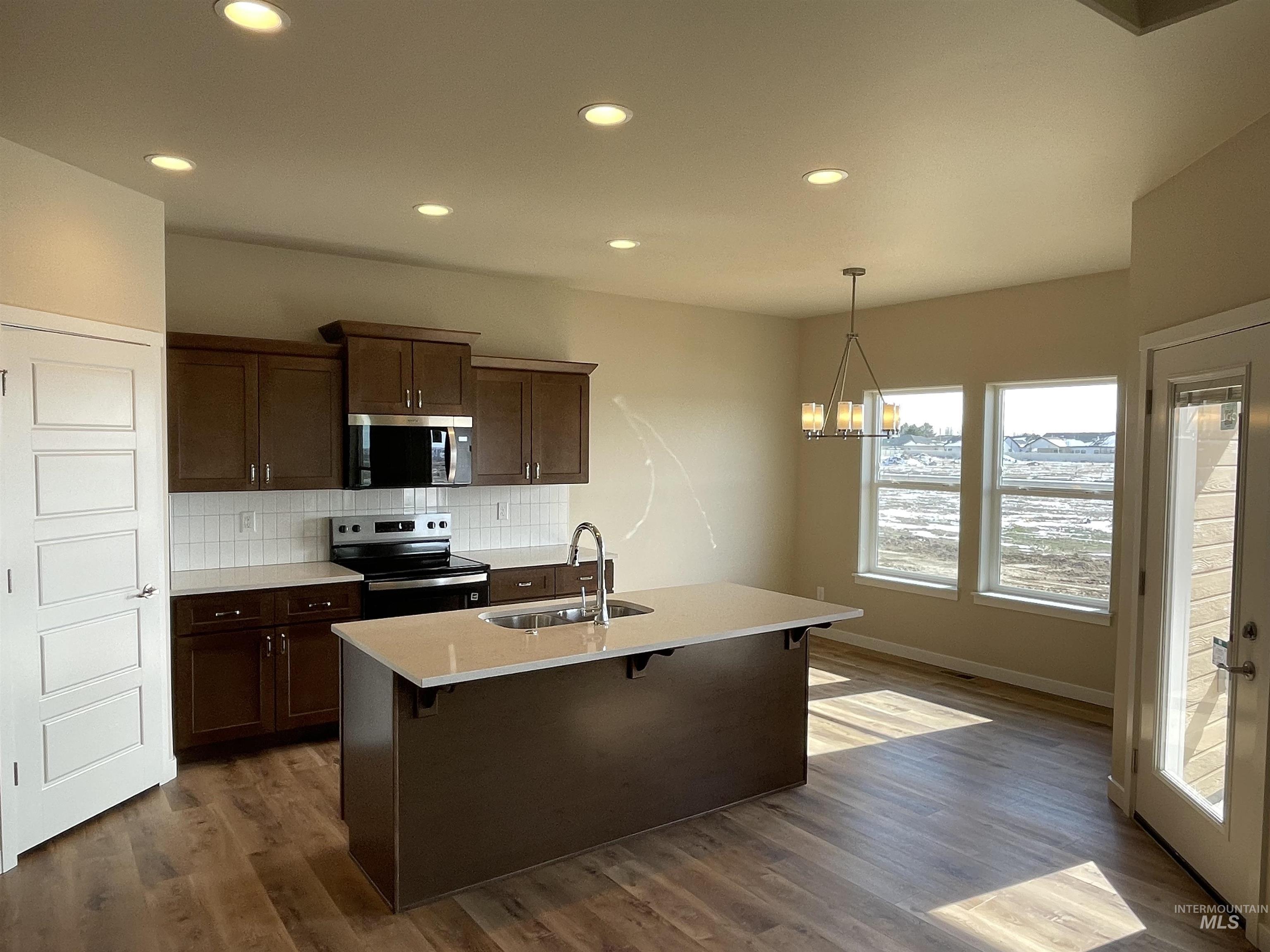 961 Quartz Road Kimberly, ID 83341 - Photo 2 of 19 Kitchen featuring stainless steel appliances, a kitchen breakfast bar, a kitchen island with sink, backsplash, and hanging lights