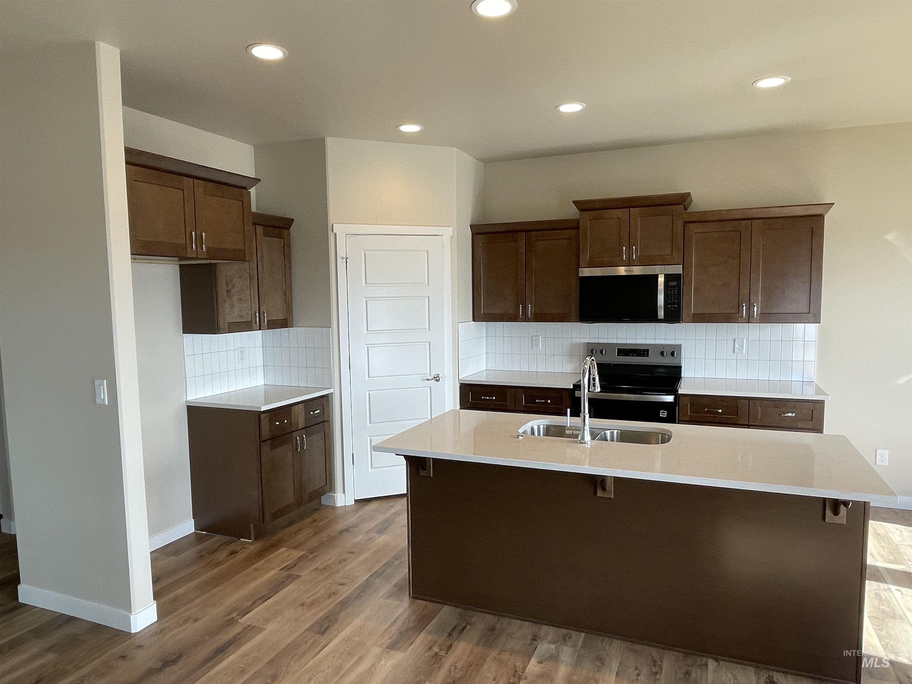 961 Quartz Road Kimberly, ID 83341 - Photo 3 of 19 Kitchen featuring decorative backsplash, stainless steel appliances, light stone counters, a center island with sink, and a breakfast bar