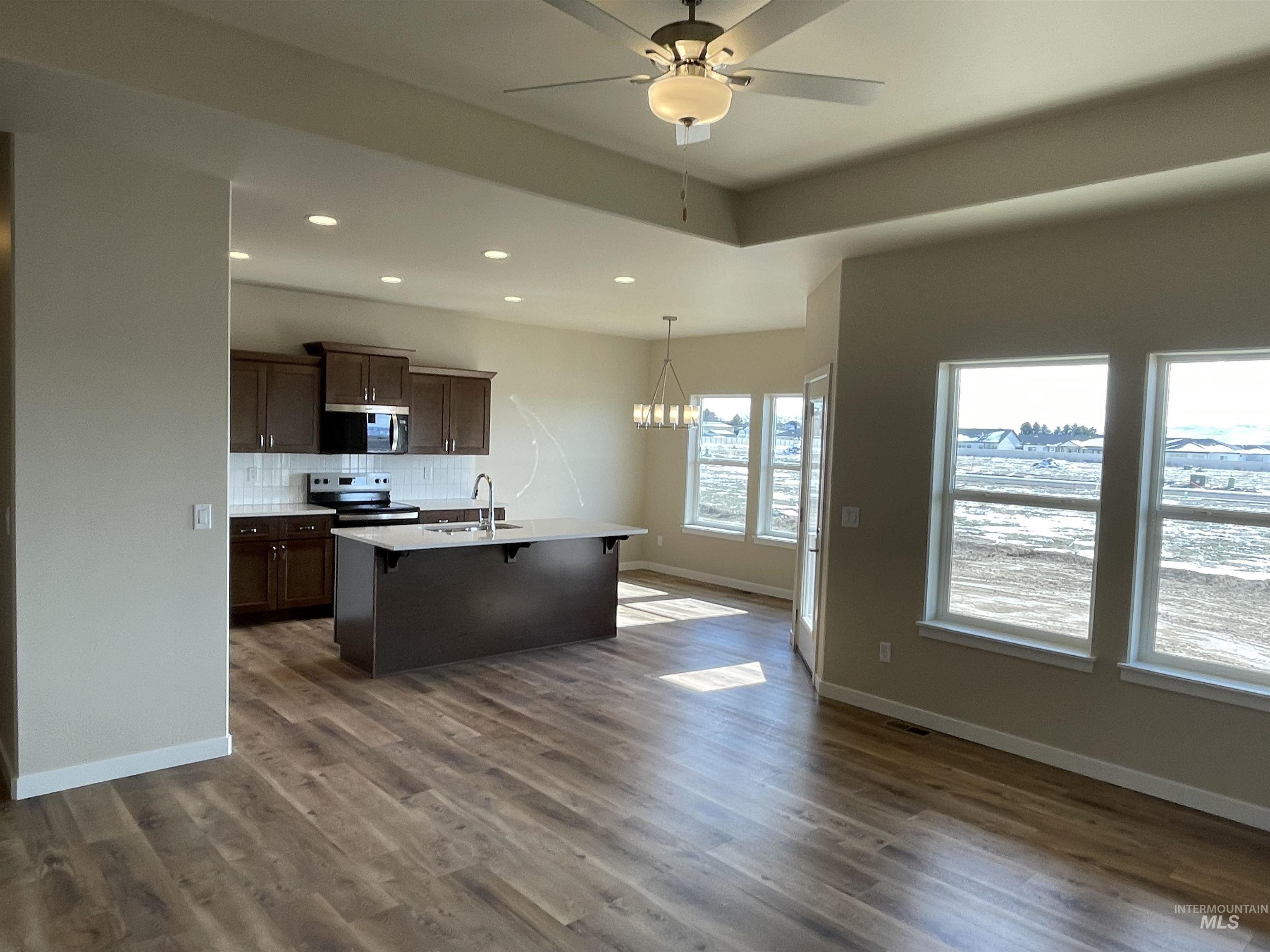 961 Quartz Road Kimberly, ID 83341 - Photo 4 of 19 Kitchen with tasteful backsplash, a kitchen bar, a chandelier, dark wood-style floors, and stainless steel appliances