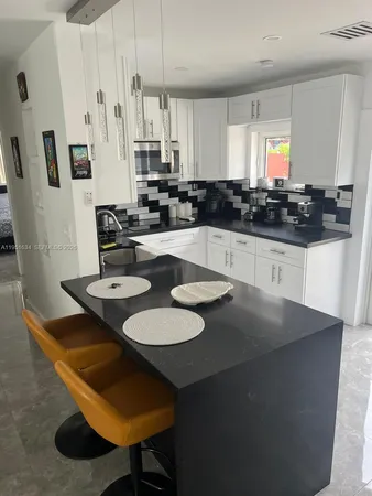 a kitchen with stainless steel appliances granite countertop a sink a stove a dining table and chairs