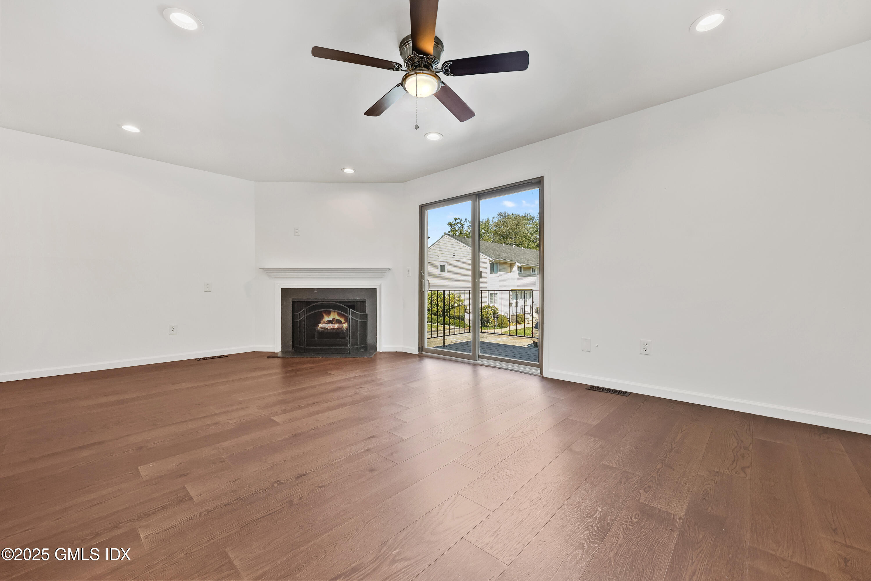 75 Cos Cob Avenue, Unit 14 Cos Cob, CT 06807 - Photo 7 of 28 an empty room with windows fireplace and a ceiling fan
