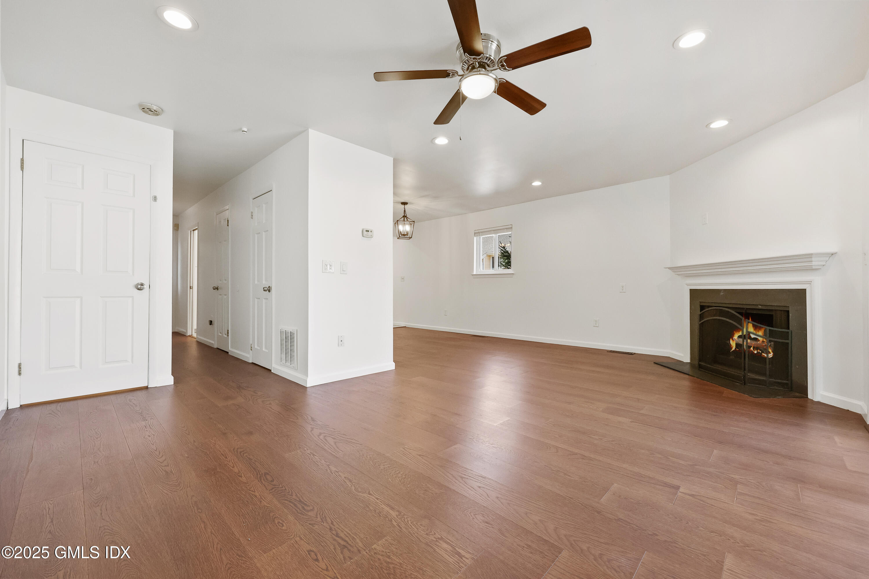 75 Cos Cob Avenue, Unit 14 Cos Cob, CT 06807 - Photo 9 of 28 an empty room with wooden floor a ceiling fan a fireplace and windows