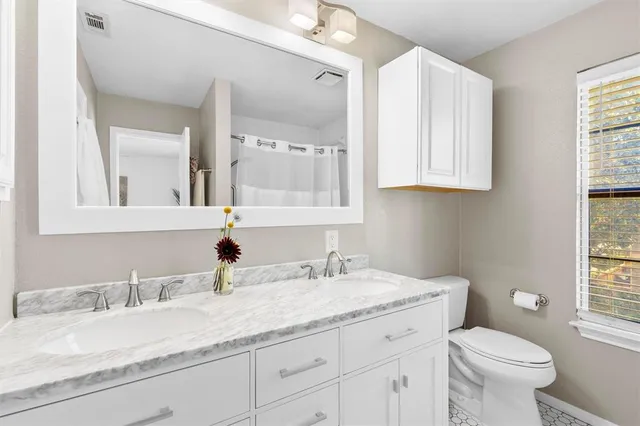 a bathroom with a granite countertop sink a toilet and a mirror