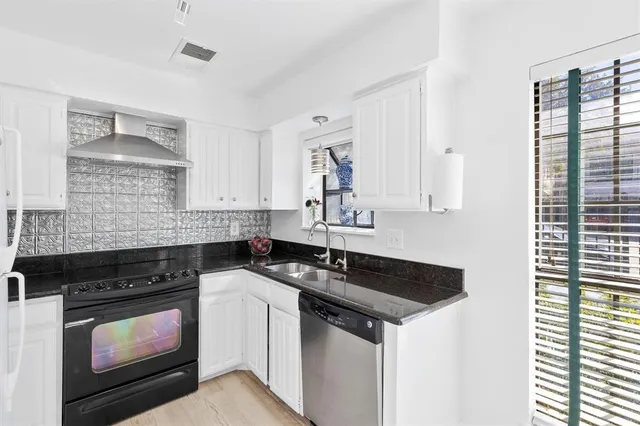 a kitchen with granite countertop a sink a stove and cabinets
