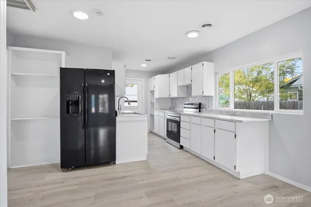 a kitchen with granite countertop a refrigerator and a stove top oven