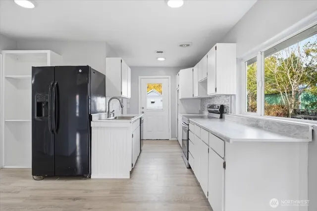 a kitchen with stainless steel appliances granite countertop a refrigerator a sink dishwasher a stove and a refrigerator