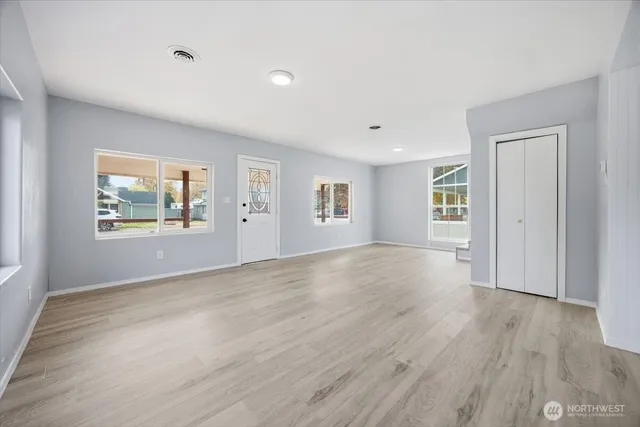 a view of an empty room with wooden floor and a window