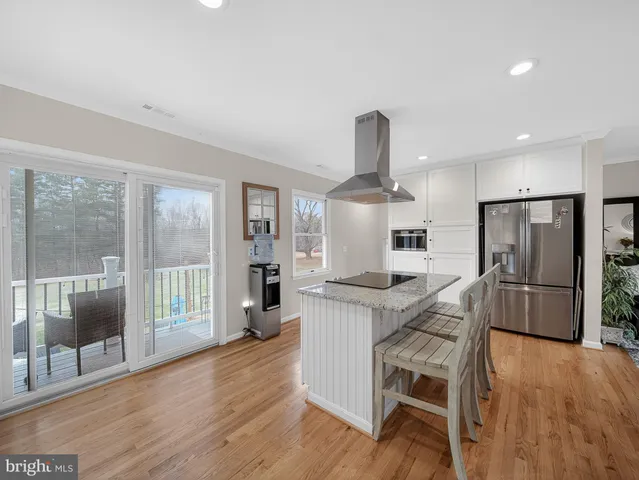 a kitchen with stainless steel appliances a dining table chairs and wooden floors